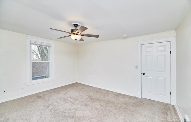 carpeted spare room with baseboards, a ceiling fan, and visible vents