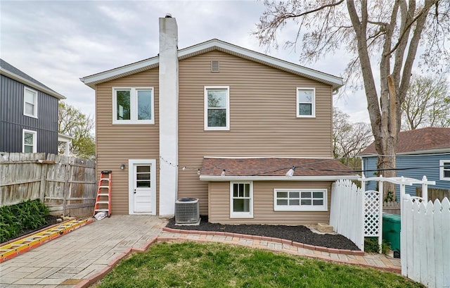 back of property featuring central AC unit, a chimney, a patio area, and fence