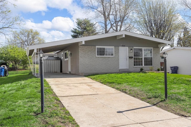 view of front of home with a carport, fence, concrete driveway, brick siding, and a front lawn