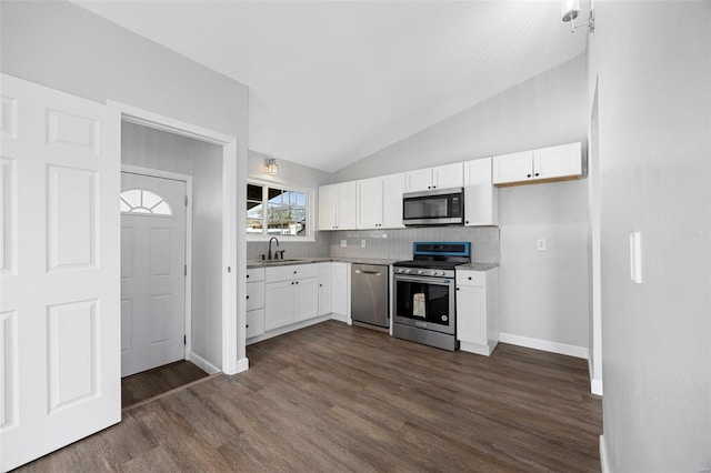 kitchen featuring dark wood-style flooring, white cabinetry, vaulted ceiling, and stainless steel appliances