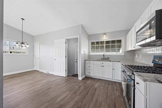 kitchen with an inviting chandelier, a sink, white cabinetry, stainless steel appliances, and dark wood-type flooring