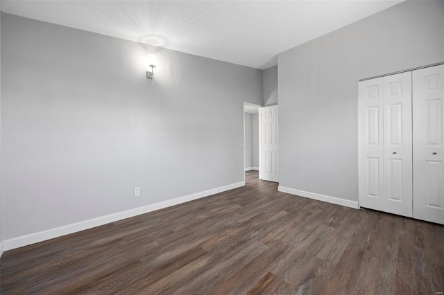 unfurnished bedroom with a closet, baseboards, and dark wood-style floors