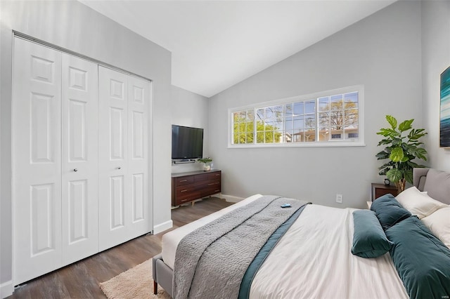 bedroom featuring a closet, dark wood-style flooring, baseboards, and lofted ceiling