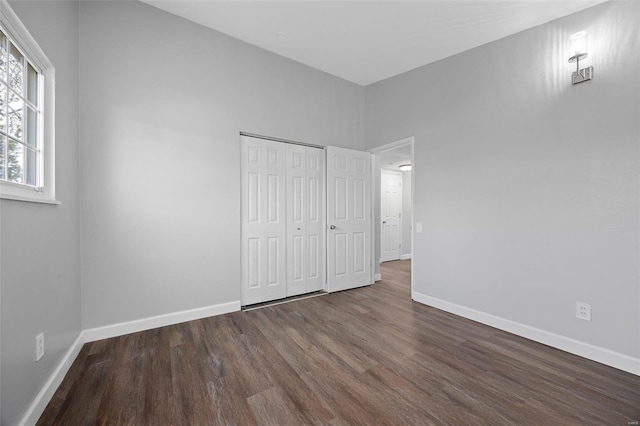 unfurnished bedroom with a closet, baseboards, and wood finished floors