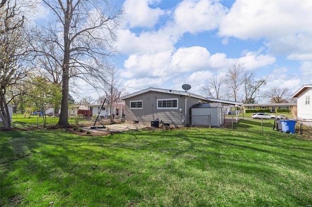 rear view of property with a yard, a storage unit, fence, and an outdoor structure