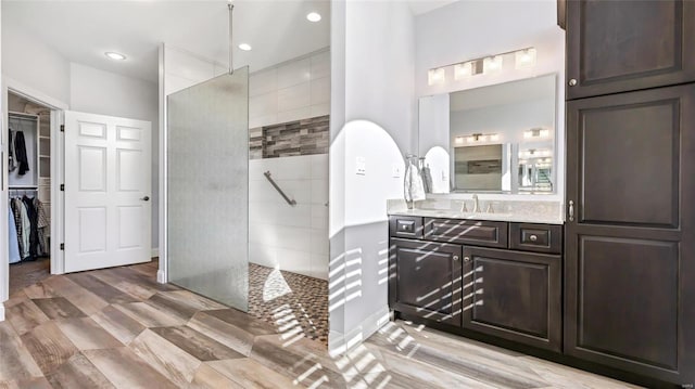 bathroom with vanity, a walk in closet, recessed lighting, and a walk in shower