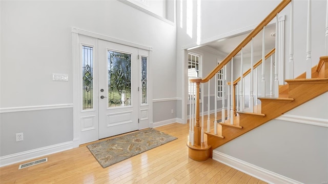 entryway with baseboards, visible vents, stairway, and hardwood / wood-style flooring