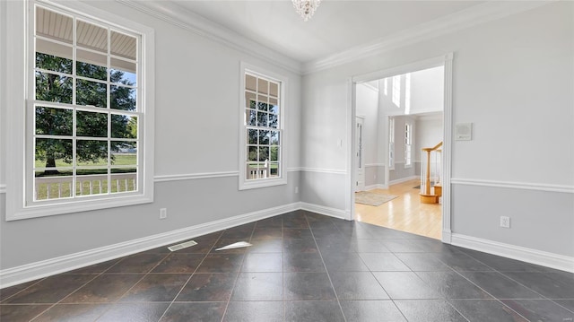 tiled empty room with plenty of natural light, baseboards, and crown molding