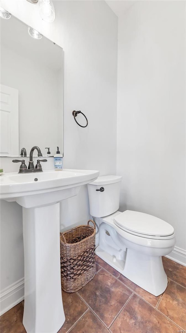 bathroom featuring baseboards, toilet, a sink, and tile patterned floors