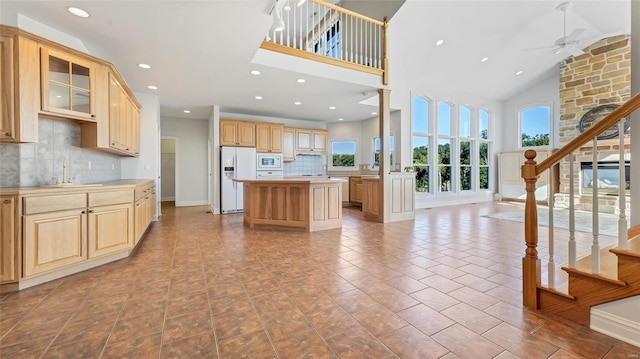 kitchen featuring light countertops, a center island, glass insert cabinets, white appliances, and ceiling fan
