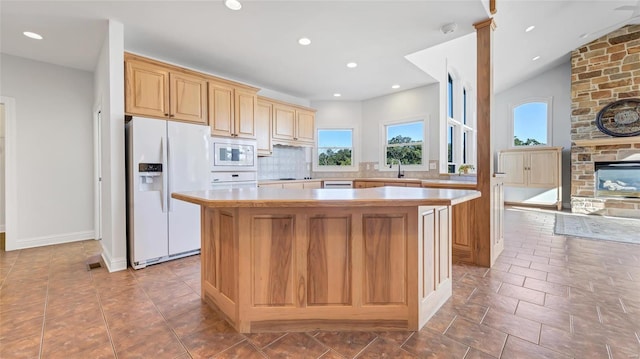kitchen with light countertops, plenty of natural light, a center island, and white appliances