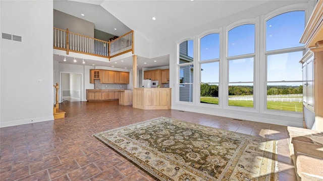 unfurnished living room with baseboards, visible vents, a towering ceiling, and recessed lighting