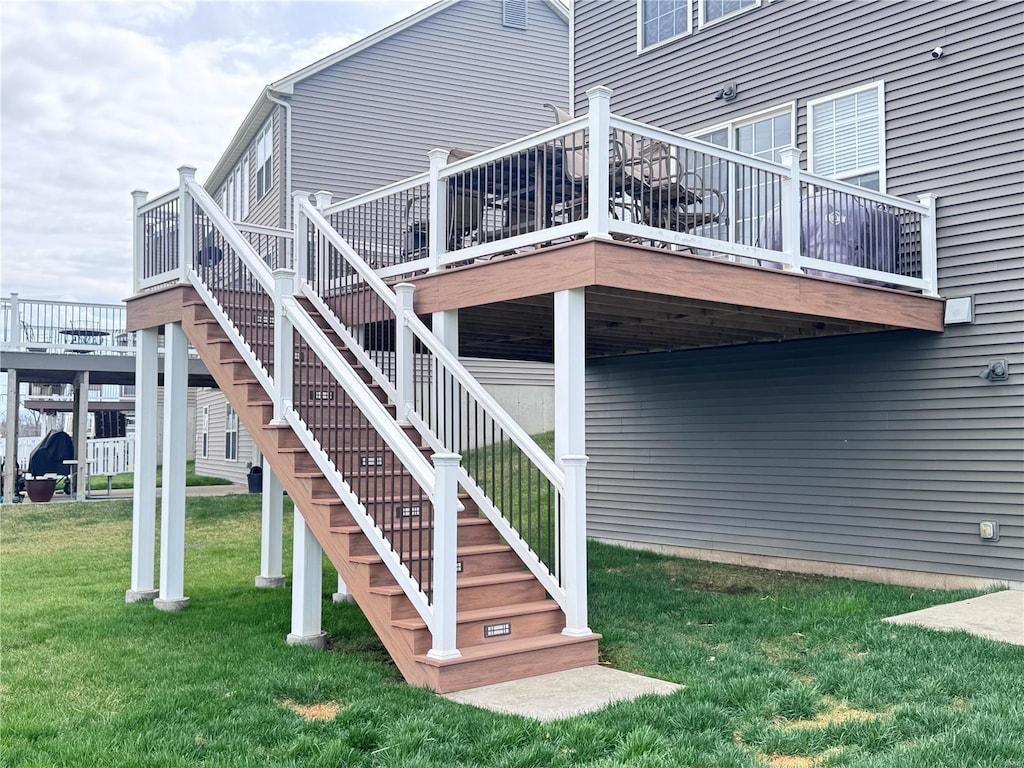 rear view of house featuring stairway, a yard, and a deck
