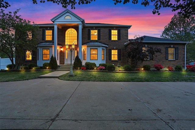 view of front of property with a front lawn, a standing seam roof, and brick siding