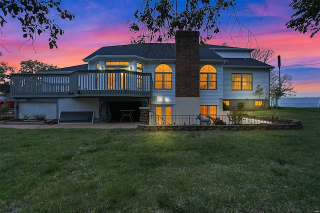rear view of house featuring a lawn, a deck, a patio area, and a chimney