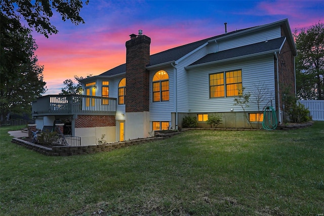 rear view of property with a lawn, fence, a chimney, and a deck