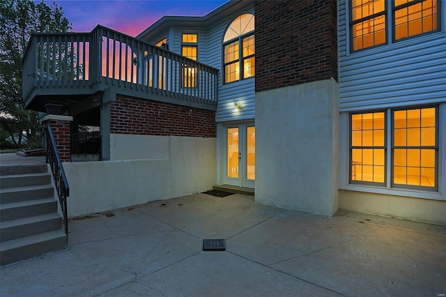 back of house at dusk featuring a patio and brick siding