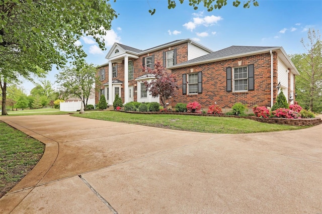 greek revival house featuring a front lawn and brick siding