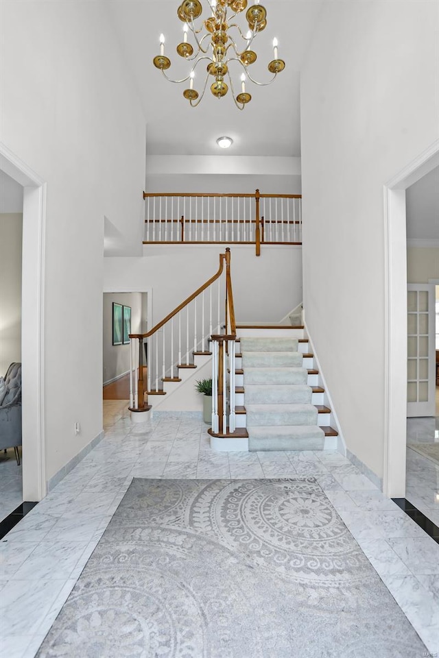 stairs with baseboards, an inviting chandelier, and marble finish floor