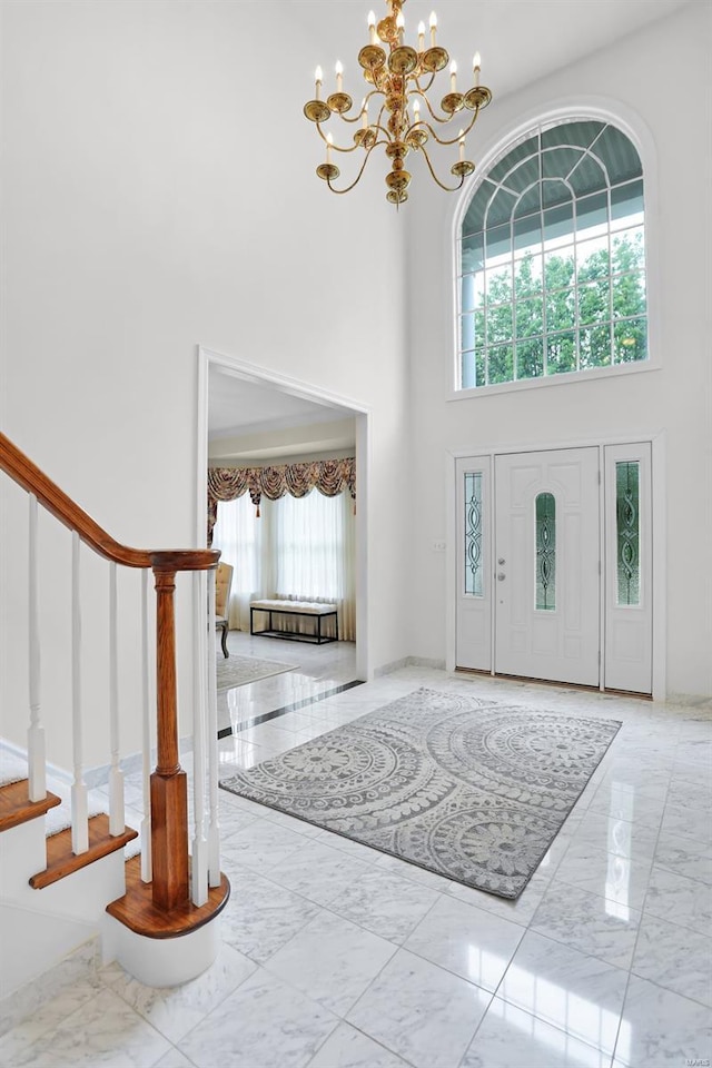 foyer entrance featuring a chandelier, stairway, a high ceiling, and marble finish floor
