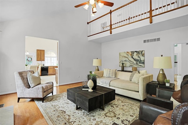 living area featuring high vaulted ceiling, ceiling fan, light wood-style floors, and visible vents