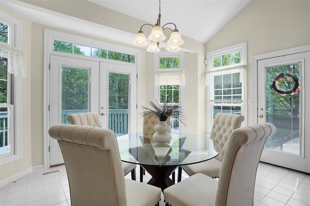 dining room with lofted ceiling, light tile patterned flooring, an inviting chandelier, and baseboards