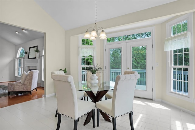 dining room with a fireplace, lofted ceiling, a chandelier, and baseboards