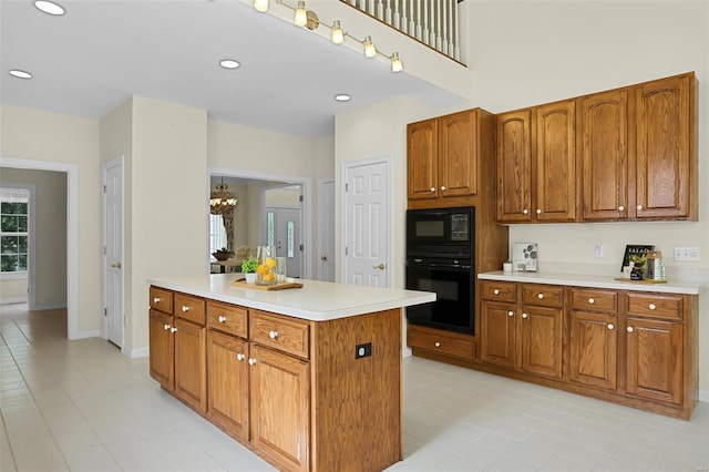 kitchen featuring light tile patterned floors, black appliances, brown cabinets, and light countertops