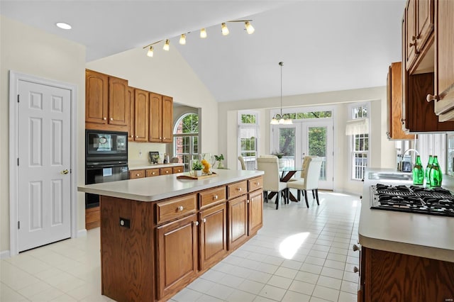kitchen with light tile patterned floors, a center island, stovetop with downdraft, light countertops, and lofted ceiling