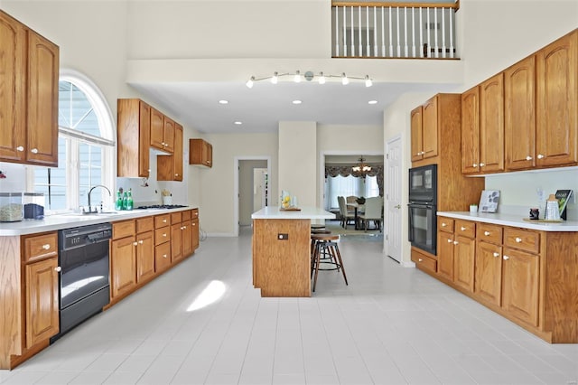 kitchen with brown cabinets, a sink, a breakfast bar, a kitchen island, and black appliances