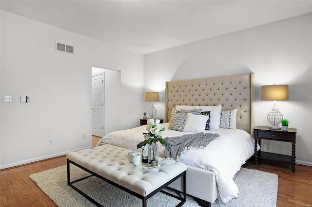 bedroom with wood finished floors, visible vents, and baseboards