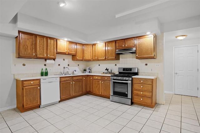 kitchen with stainless steel gas range, a sink, under cabinet range hood, white dishwasher, and light countertops