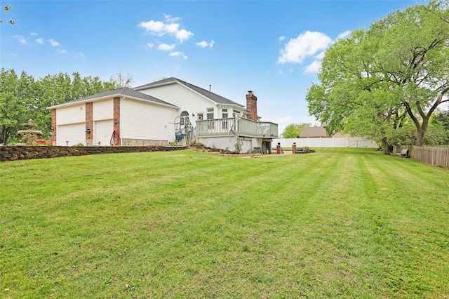 view of yard featuring fence, a deck, and a garage
