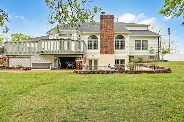 back of house featuring a deck, a chimney, a yard, fence, and a shingled roof