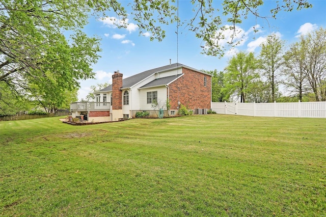 back of property with central AC, a chimney, a yard, brick siding, and a fenced backyard
