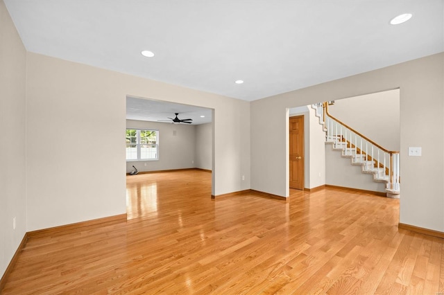 unfurnished living room featuring baseboards, recessed lighting, stairs, and light wood finished floors