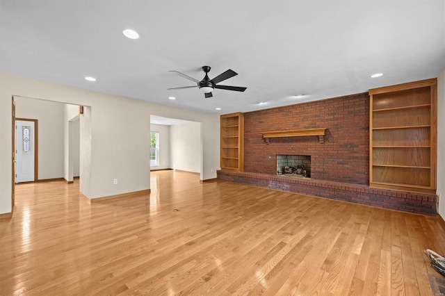 unfurnished living room featuring ceiling fan, a fireplace, light wood-style floors, built in features, and baseboards