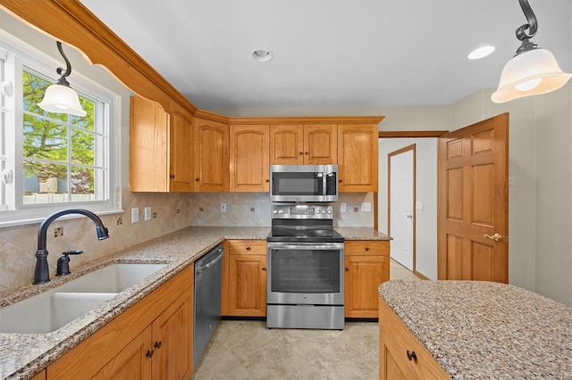 kitchen with stainless steel appliances, light stone countertops, a sink, and tasteful backsplash