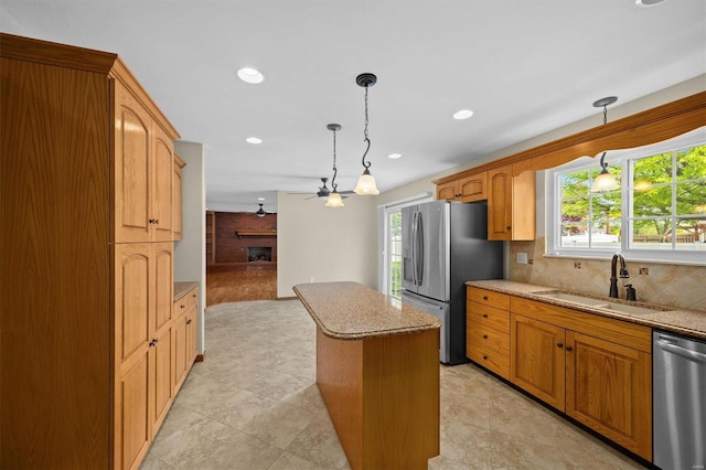 kitchen featuring light stone counters, a sink, a center island, stainless steel appliances, and backsplash