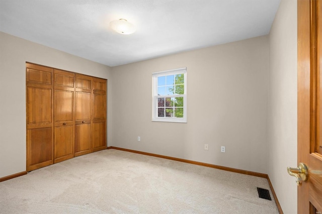 unfurnished bedroom featuring baseboards, light carpet, and visible vents