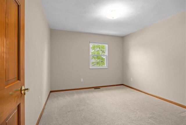 carpeted empty room featuring baseboards and visible vents