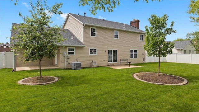 rear view of property with a lawn, a chimney, a fenced backyard, and a patio area