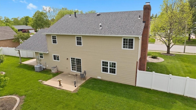 back of property with roof with shingles, a chimney, a patio area, central air condition unit, and a yard