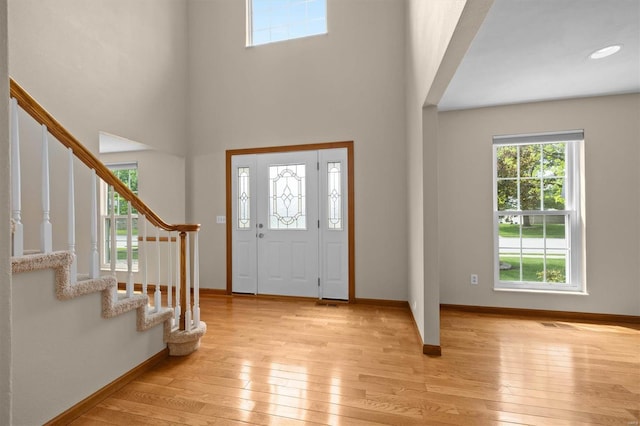 entryway with stairway, baseboards, a healthy amount of sunlight, and light wood finished floors