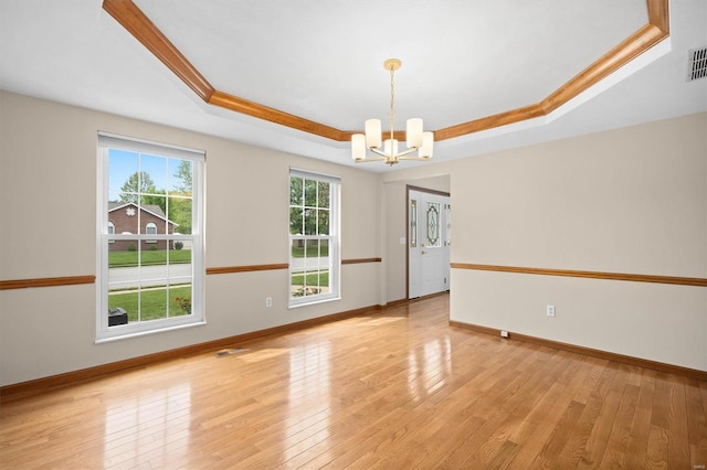 spare room with baseboards, a notable chandelier, light wood-style flooring, and a raised ceiling
