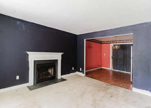 unfurnished living room featuring baseboards, an inviting chandelier, a fireplace with flush hearth, and an accent wall