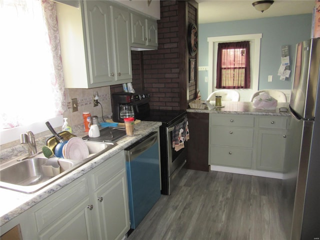 kitchen with light countertops, a sink, appliances with stainless steel finishes, dark wood finished floors, and white cabinets