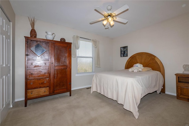 bedroom featuring a ceiling fan, light carpet, a closet, and baseboards