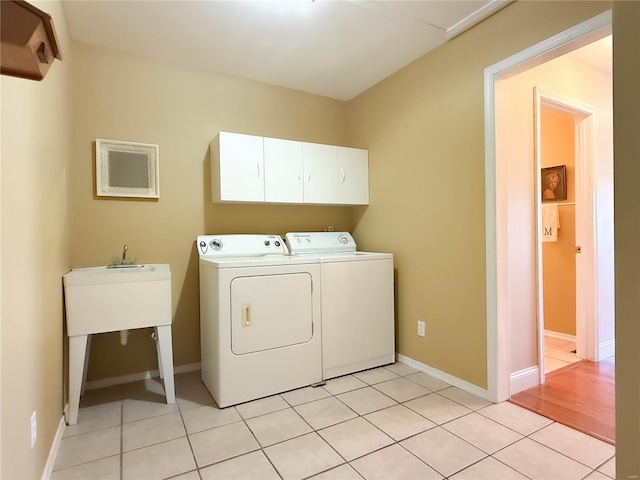 laundry area with washing machine and clothes dryer, cabinet space, light tile patterned flooring, and baseboards
