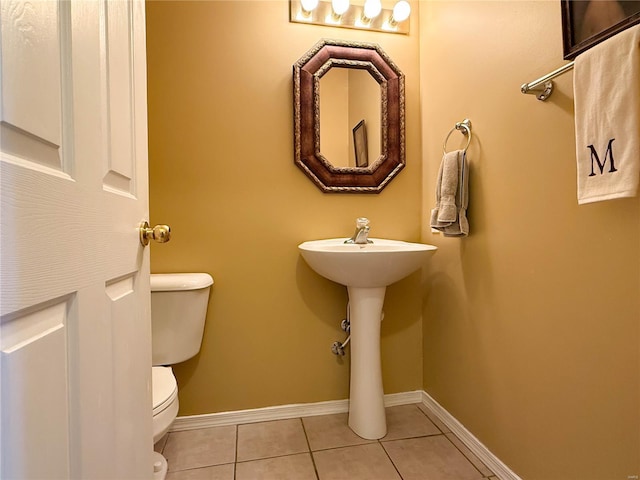 half bathroom featuring baseboards, tile patterned flooring, and toilet